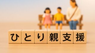 「ひとり親支援」のウッドブロック文字と、背景にミニチュアの母親と子どもがぼんやりと写っている写真。公的制度や子育て支援をテーマにしたイメージ。